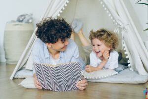 young mother reading a book to her preschooler in a playroom tent